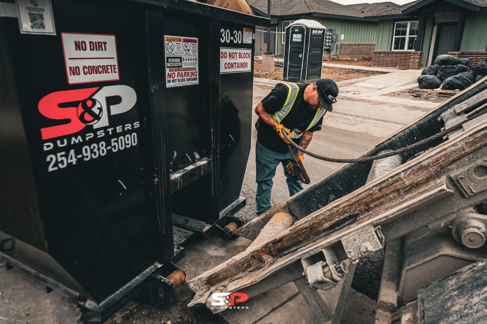 An S&P Dumpsters crew member loading lumber into a container